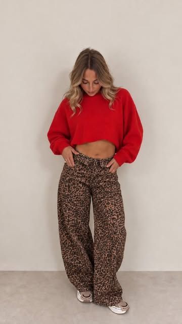 Model in rotem Pullover und Hose mit Leomuster